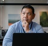 cropped-pexels-photo-5668885-5668885.jpg A businessman deep in thought while working on a laptop in a modern office setting.